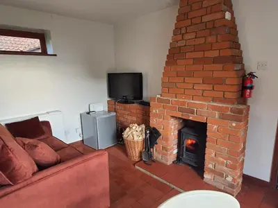 a living room with a brick fireplace and a couch at Cosy Rural Barn Conversion 5 Min Drive To Pin Mill 1 BR + sofa bed in Chelmondiston