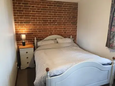 a bedroom with a white bed and a brick wall at Cosy Rural Barn Conversion 5 Min Drive To Pin Mill 1 BR + sofa bed in Chelmondiston