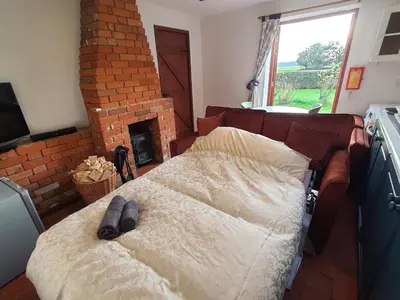 a bedroom with a bed and a brick fireplace at Cosy Rural Barn Conversion 5 Min Drive To Pin Mill 1 BR + sofa bed in Chelmondiston