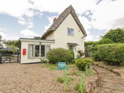 a white cottage with a thatched roof at Waveney Cottage in Diss