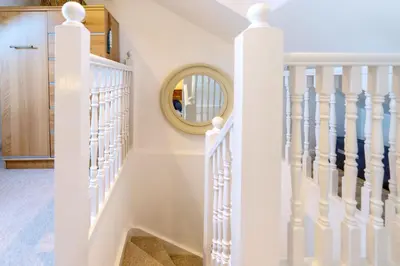 a white staircase with a round mirror on the wall at The Bolthole in Aldeburgh