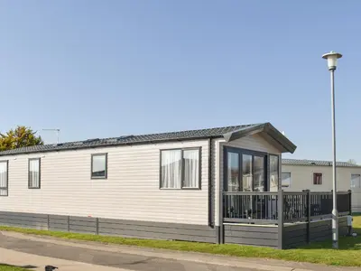 a white house with a porch on a street at West Mersea Park in West Mersea