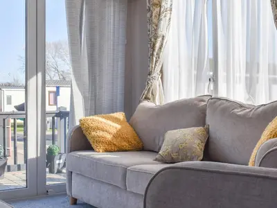 a gray couch with pillows in a room with a window at West Mersea Park in West Mersea