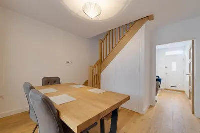 a dining room with a wooden table and a staircase at Bright Beautiful Modern 2 Bed Home Pass The Keys in Cambridge