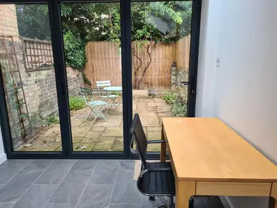 an office with a desk and a table and a patio at Bright Beautiful Modern 2 Bed Home Pass The Keys in Cambridge