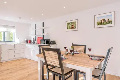 a kitchen and dining room with a wooden table and chairs at Little Honey Pot, Benhall in Saxmundham