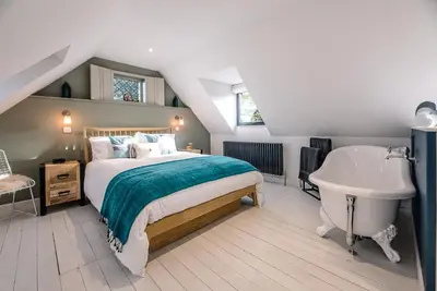 a bedroom with a bed and a tub and a sink at Little Honey Pot, Benhall in Saxmundham