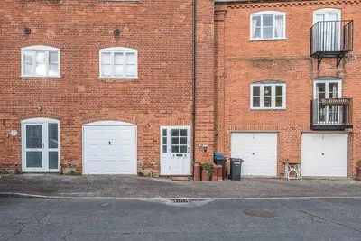 a brick building with four white garage doors at 4 Ropers Court, Lavenham in Lavenham