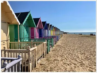 a row of colorful beach huts on the beach at Wellie Stern in Harwich