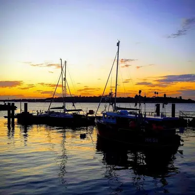 a group of boats docked in the water at sunset at Wellie Stern in Harwich