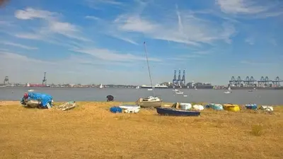 a group of boats sitting on the grass near the water at Wellie Stern in Harwich