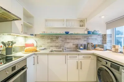 a white kitchen with a sink and a dishwasher at 1 King Street in Aldeburgh
