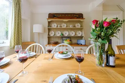 a table with glasses of wine and a vase of flowers at 9 Whinlands in Thorpeness