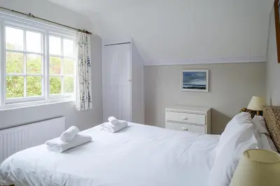 a bedroom with a white bed with towels on it at 9 Whinlands in Thorpeness