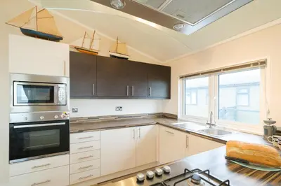 a kitchen with wooden cabinets and a stove top oven at San Remo in Sizewell