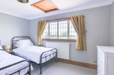a bedroom with two beds and a window at Beautiful thatched Dynes Cottage Finchingfield sleeps 10 in Finchingfield
