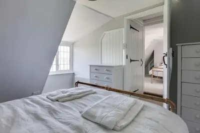a white bedroom with a bed and a dresser at Beautiful thatched Dynes Cottage Finchingfield sleeps 10 in Finchingfield