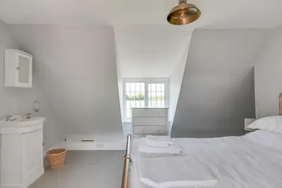 a white bedroom with a bed and a sink at Beautiful thatched Dynes Cottage Finchingfield sleeps 10 in Finchingfield