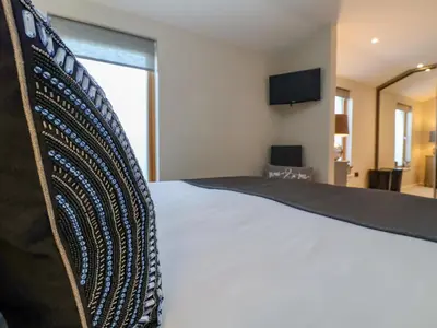 a bedroom with a white bed and a television at The Penthouse in Woodbridge