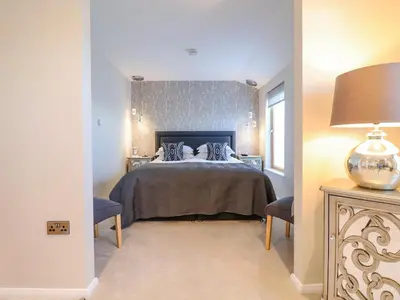 a bedroom with a bed and two chairs and a lamp at The Penthouse in Woodbridge