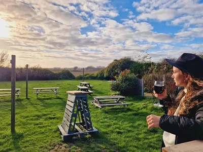a woman holding a glass of wine in a field at The Jolly Sailor, Orford in Orford