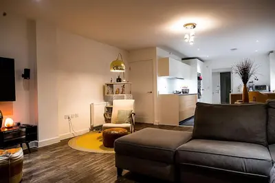 a living room with a couch and a kitchen at Exquisite cozy house, close to Train Station and amenities in Harold Wood