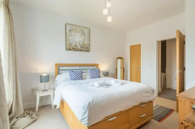 a bedroom with a large bed with a wooden dresser at Charming & Spacious House With FREE PARKING in Chesterton