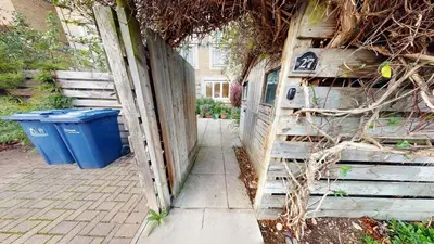 a wooden fence with a trash can next to a house at Charming & Spacious House With FREE PARKING in Chesterton