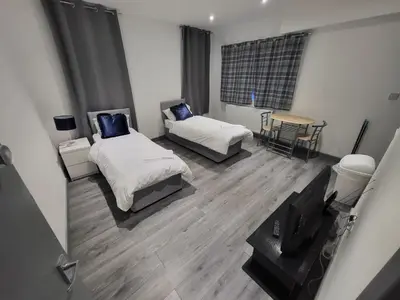 a room with two beds and a table and a television at Vetrelax Southend Suites- Sleeps up to 5 - Free Wi-Fi - Contractors - Families- Free Parking- Long Term Stays in Southend-on-Sea