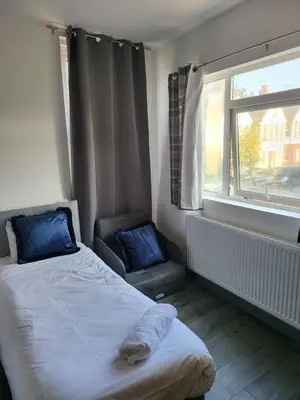 a bedroom with a bed with blue pillows and a window at Vetrelax Southend Suites- Sleeps up to 5 - Free Wi-Fi - Contractors - Families- Free Parking- Long Term Stays in Southend-on-Sea
