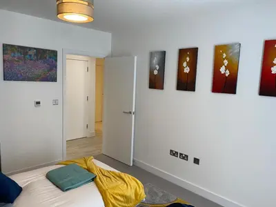 a bedroom with a bed and paintings on the wall at Exquisite & Contemporary 2 Bed Apartment w Parking 10 mins walk to Papworth, Addenbrookes hospitals & Bio Medical Campus in Trumpington
