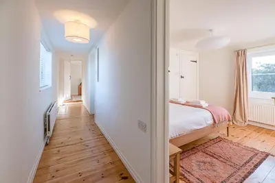 a bedroom with a bed and a hallway with a window at Solebay House, Tunstall in Woodbridge