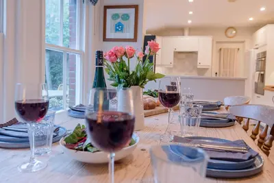 a table with glasses of wine and flowers on it at 18 Hartington, Aldeburgh in Aldeburgh