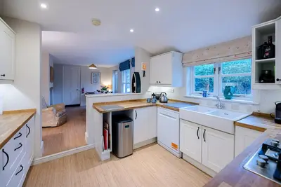a large kitchen with white cabinets and a sink at 18 Hartington, Aldeburgh in Aldeburgh