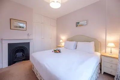 a bedroom with a white bed and a fireplace at 18 Hartington, Aldeburgh in Aldeburgh