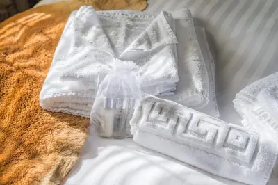 a pile of towels and a bottle on a bed at Deluxe 2 Bed Versace Bungalow Hot Tub, Sky TV, Cinema Screen Saffron Walden in Saffron Walden
