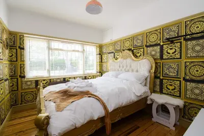 a bedroom with a large bed with ornate wallpaper at Deluxe 2 Bed Versace Bungalow Hot Tub, Sky TV, Cinema Screen Saffron Walden in Saffron Walden
