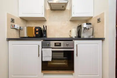 a kitchen with white cabinets and a counter top at Deluxe 2 Bed Versace Bungalow Hot Tub, Sky TV, Cinema Screen Saffron Walden in Saffron Walden