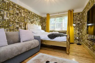 a bedroom with a bed and a couch at Deluxe 2 Bed Versace Bungalow Hot Tub, Sky TV, Cinema Screen Saffron Walden in Saffron Walden