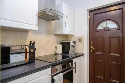 a kitchen with white cabinets and a brown door at Deluxe 2 Bed Versace Bungalow Hot Tub, Sky TV, Cinema Screen Saffron Walden in Saffron Walden