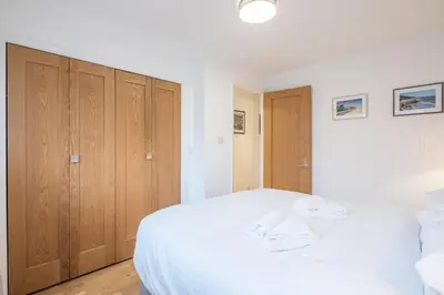 a bedroom with a white bed and wooden cabinets at Modern & Private - Free Parking in Cherry Hinton