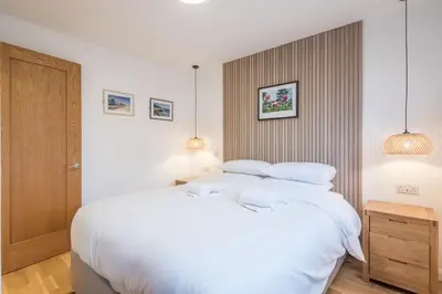 a bedroom with a large bed with white sheets at Modern & Private - Free Parking in Cherry Hinton
