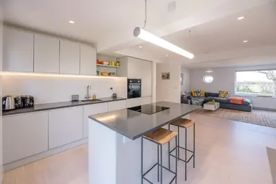 a kitchen and living room with white cabinets and a counter at Chapel House, Alderton in Woodbridge