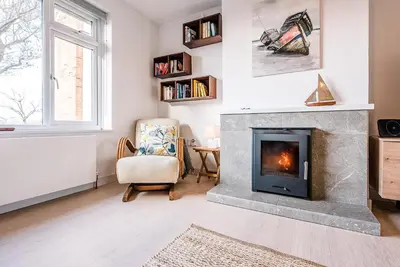 a living room with a fireplace and a chair at Chapel House, Alderton in Woodbridge