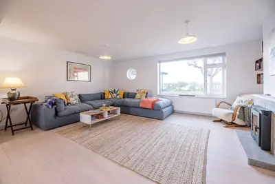 a living room with a blue couch and a fireplace at Chapel House, Alderton in Woodbridge