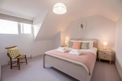 a bedroom with a large bed and a chair at Chapel House, Alderton in Woodbridge