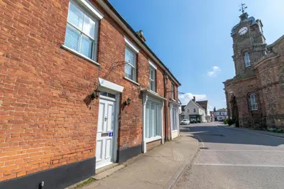 a brick building with a white door and a clock tower at 2 Bed in Eye oc-4lamb in Eye