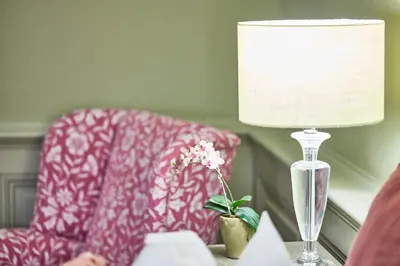 a lamp on a table next to a chair and a flower at The Mistley Thorn in Mistley