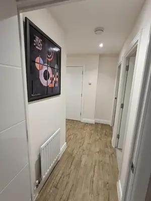a hallway with white walls and a painting on the wall at Stunning 2-Bed Apartment in Stevenage, Sleeps 5 with free Private Parking in Stevenage