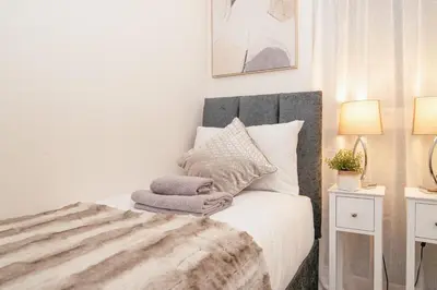 a bedroom with a bed with a blanket and two lamps at Stunning 2-Bed Apartment in Stevenage, Sleeps 5 with free Private Parking in Stevenage
